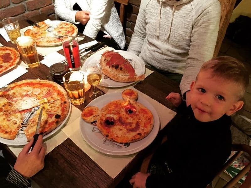 Familie mit kleinem Kind isst gemeinsam Pizza im Gastraum
