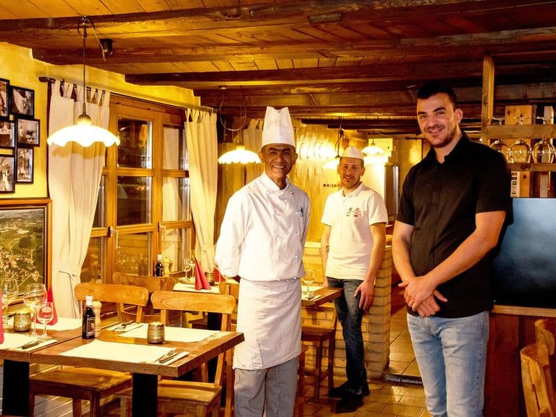 Küchenchef und Team stehen lächelnd im Gastraum